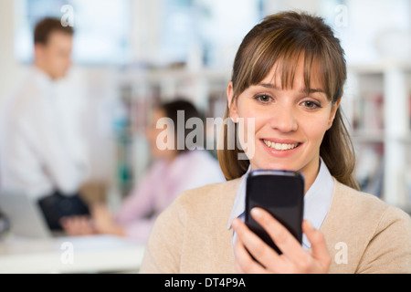 Cheerful businesswoman using a smart phone in office Stock Photo