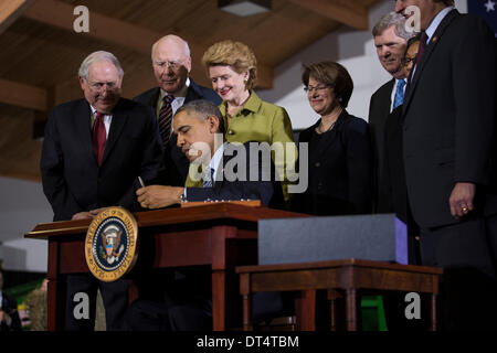 US President Barack Obama signs the Agricultural Act of 2014 known as the Farm Bill during a ceremony at Michigan State University February 7, 2014 in East Lansingg, MI. Standing with the president are (L-R) Senators Carl Levin, Patrick Leahy, Debbie Stabenow, Amy Klobuchar and Agriculture Secretary Tom Vilsack. Stock Photo