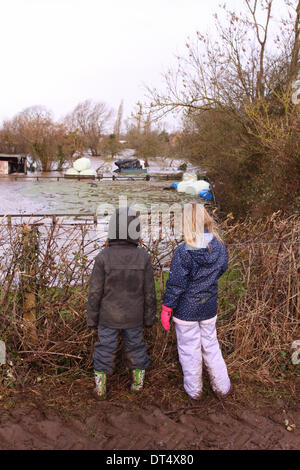 Burrowbridge, Somerset, UK. 9th Feb 2014. Two young children look at the flotsam and jetsam floating among the flooded fields at Burrowbridge in The Somerset levels. Stock Photo