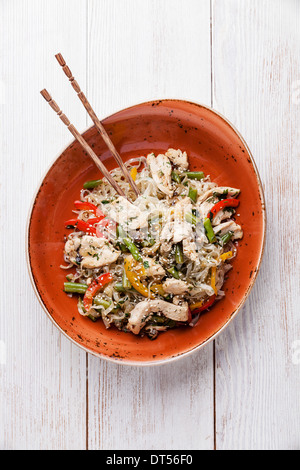 Stir fry chicken with vegetables and rice noodles on red plate Stock Photo