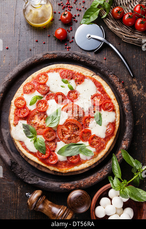 Italian pizza with tomatoes and mozzarella on wooden table Stock Photo