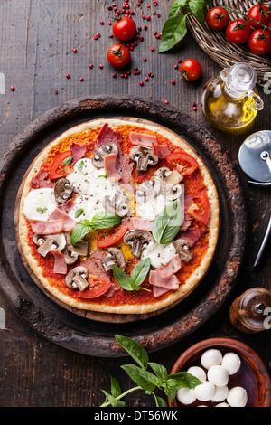 Italian pizza with meat, ham and mushrooms on wooden table Stock Photo