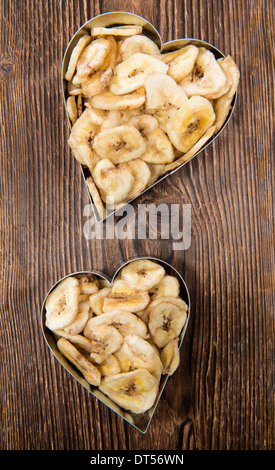 Banana Chip in heart shapes on vintage wooden background Stock Photo