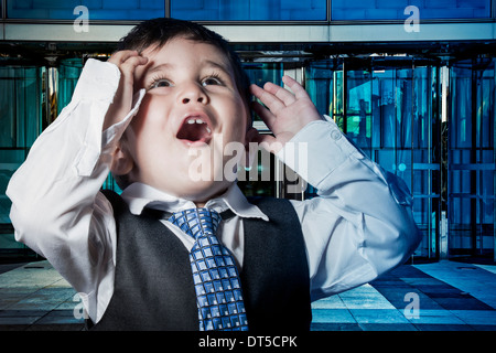 Business, child dressed businessman with hands in his tie and skyscrapers in the background Stock Photo