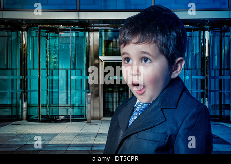 Education, child dressed businessman with hands in his tie and skyscrapers in the background Stock Photo