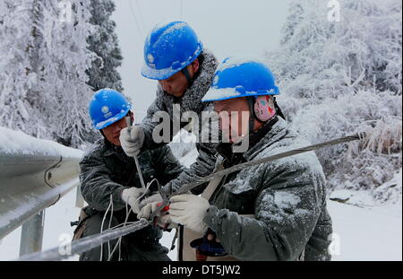 Enshi, China's Hubei Province. 9th Feb, 2014. Workers of State Grid Corporation of China repair cables in an attempt to resume power transmission after a heavy snow in Chunmuying Township of Xuan'en County in Enshi Tu and Miao Ethnic Autonomous Prefecture, central China's Hubei Province, Feb. 9, 2014. © Song Wen/Xinhua/Alamy Live News Stock Photo