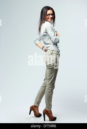 Side view portrait of a young cheerful businesswoman standing on gray background Stock Photo