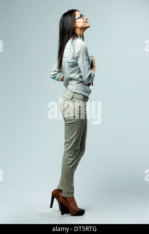 Side view portrait of a young beautiful woman looking up on gray background Stock Photo