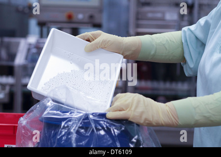 Laboratory technician emptying tablets into plastic bag Stock Photo