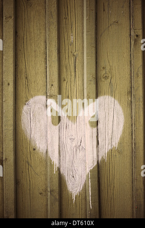 White heart with evil eyes painted on wooden wall of building Stock Photo