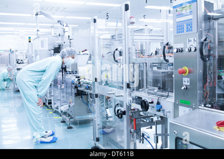 Laboratory technician bending to take closer look at machine Stock Photo