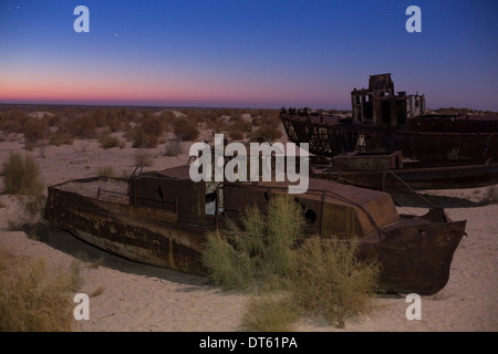 The rusty hulls of abandoned fishing boats on the the Aral Sea bed at dawn in Moynaq, northern Uzbekistan. Stock Photo