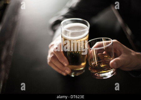 Close up of two men toasting drinks in bar