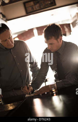 Two businessmen signing contract in wine bar Stock Photo