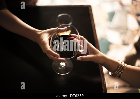 Close up of bartender serving glass of red wine to young woman Stock Photo