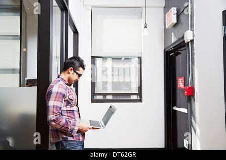 Young man holding laptop in corridor Stock Photo