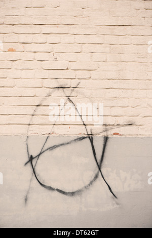 Grafitti with anarchy symbol painted on white brick wall Stock Photo