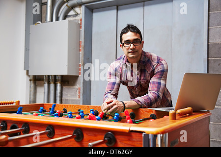 Portrait of young man leaning on table football Stock Photo