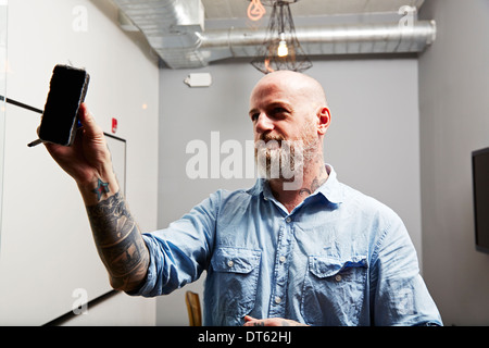 Mature man using whiteboard eraser Stock Photo