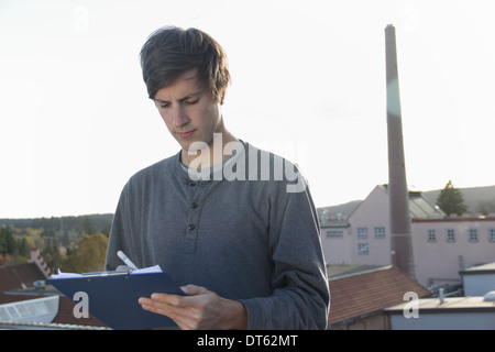 Man writing on clipboard outside brewery Stock Photo