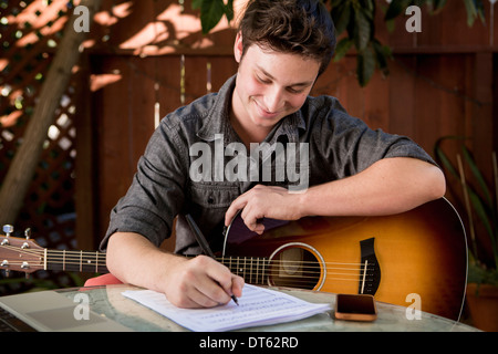 Young man composing music in garden Stock Photo