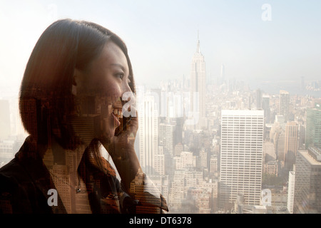 Woman using cell phone against cityscape, New York, USA Stock Photo