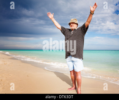 Senior man practicing yoga on beach Stock Photo
