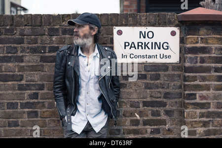Mature man by no parking sign on brick wall Stock Photo