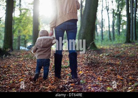 Mother and male toddler walking in woodland