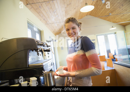 A young woman making coffee using a large coffee machine. Stock Photo