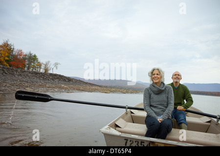 A couple, man and woman sitting in a rowing boat on the water on an autumn day. Stock Photo