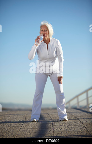 Mature woman drinking water on walk Stock Photo