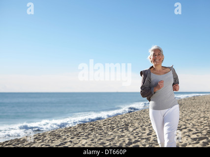 Mature woman jogging on beach Stock Photo