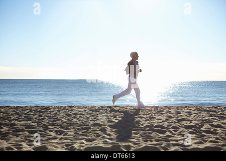 Mature woman jogging on beach Stock Photo