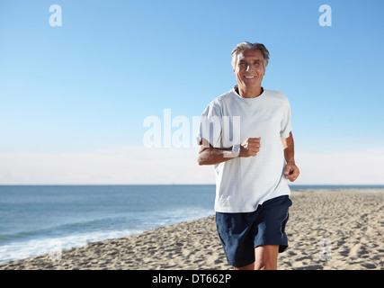 Senior man jogging on beach Stock Photo