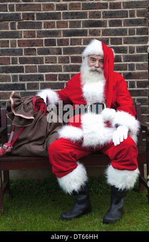 Santa Claus taking break on bench Stock Photo