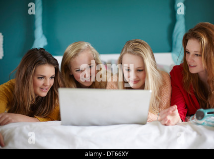 Four teenage girls looking at laptop in bedroom Stock Photo