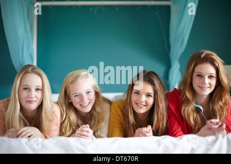 Portrait of four teenage girls lying on bed Stock Photo