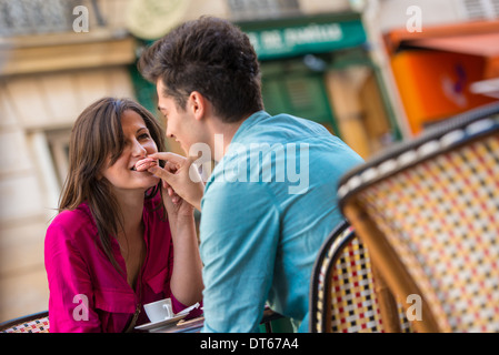 Young couple sharing macaroon at pavement cafe, Paris, France Stock Photo