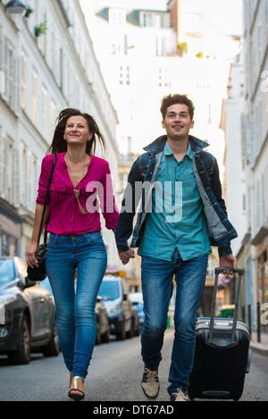 Young couple with wheeled suitcase, Paris, France Stock Photo