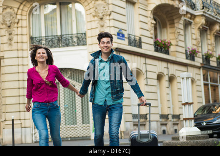 Young couple walking with wheeled suitcase, Paris, France Stock Photo