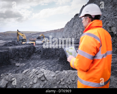 Miner checks plans on digital tablet in surface coal mine Miner checks plans on digital tablet in surface coal mine