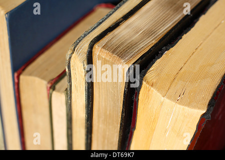 a collection of vintage hardcover books and novels are lined up in a row, seen from the top page corners Stock Photo