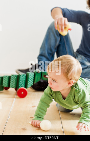 Studio shot of father and baby daughter playing on floor