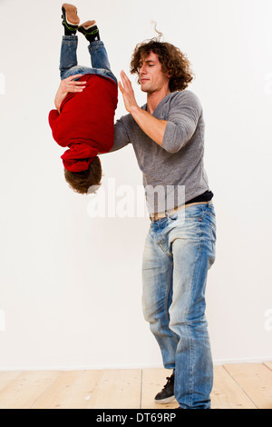 Studio shot of father turning over son in mid air Stock Photo
