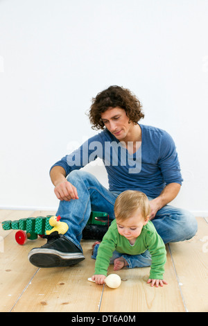 Studio shot of father and baby daughter paying on floor
