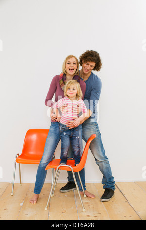 Studio shot of couple with young daughter standing on chair Stock Photo