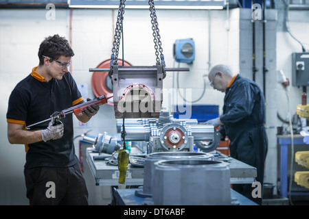 Apprentice engineer applying sealant to industrial gearbox in factory