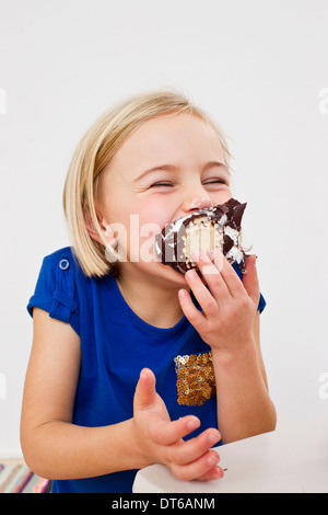 Studio portrait of young girl eating chocolate marshmallow Stock Photo