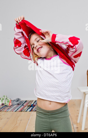 Studio shot of girl pulling off red heart sweater Stock Photo